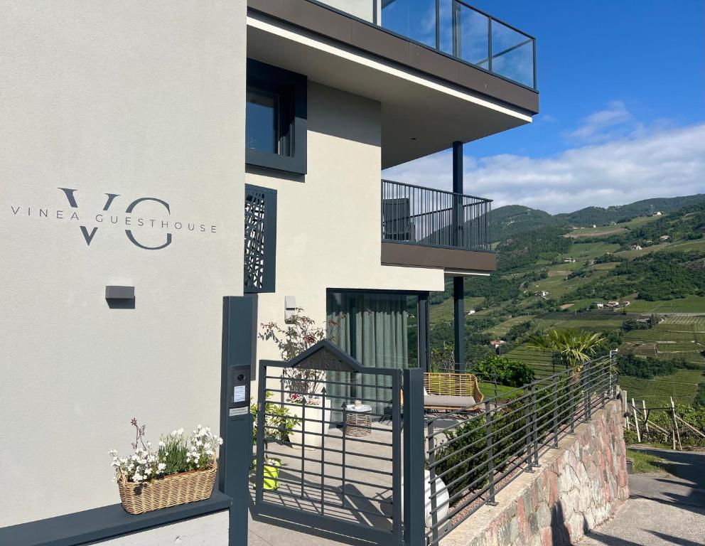 a white house with a black gate and a balcony at New Opening Vinea Guesthouse in Cornedo all'Isarco