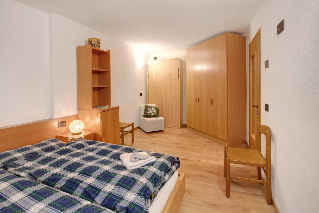 a bedroom with a bed and a chair in it at Appartamenti Vittoria Bilo in Valfurva