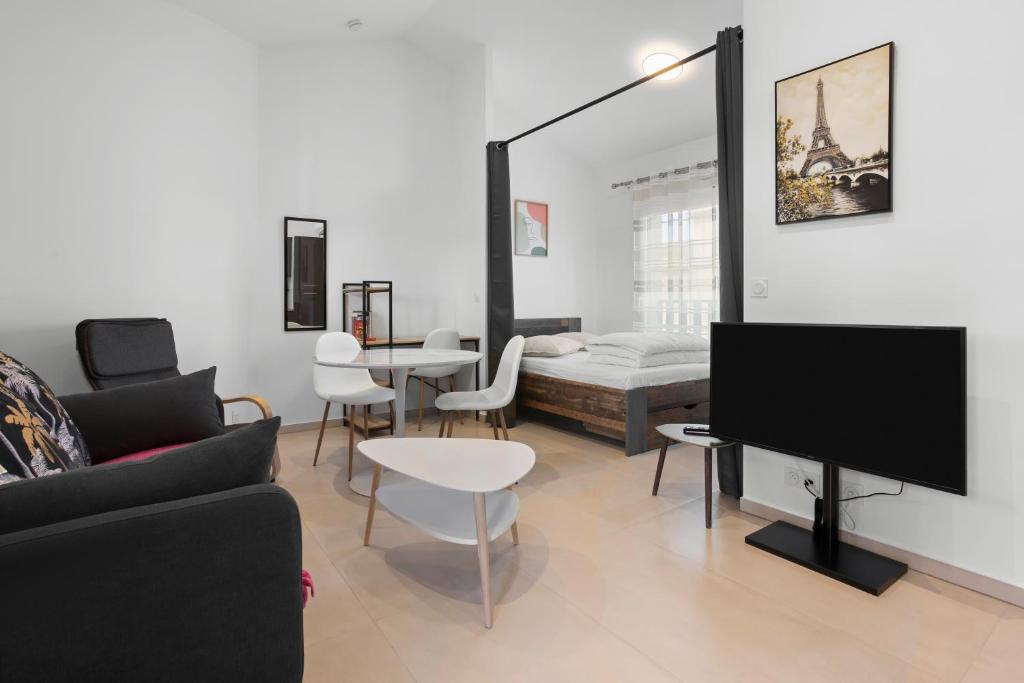 a living room with a couch and a flat screen tv at Studio 2 proche centre avec parking in Fréjus