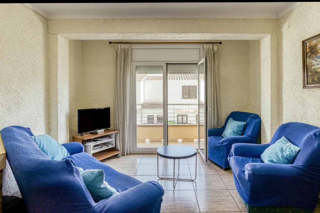 a living room with two blue chairs and a tv at Apartamento la Siesta in L'Escala