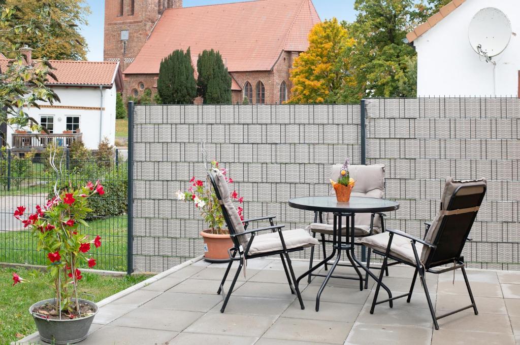 a patio with a table and chairs and a fence at Haus Kirchenblick in Kalkhorst