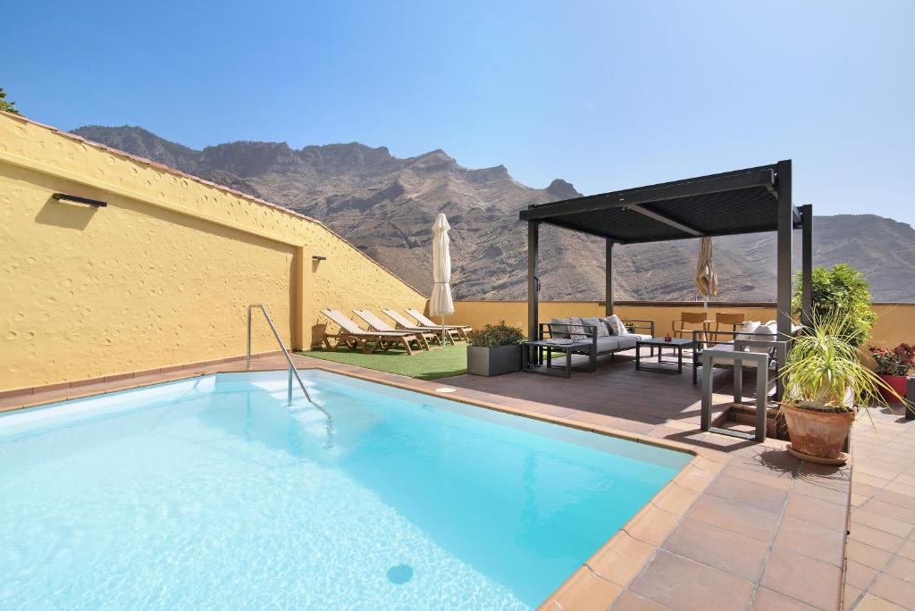 a swimming pool with a patio with a table and chairs at Los Veroles in Agaete