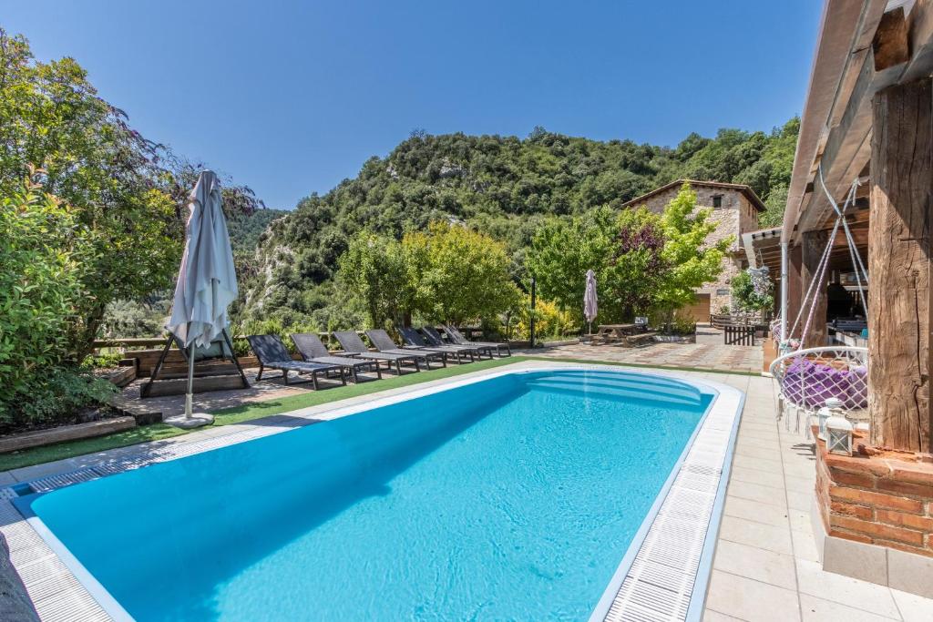 a pool with chairs and an umbrella next to a house at Moli in Oden