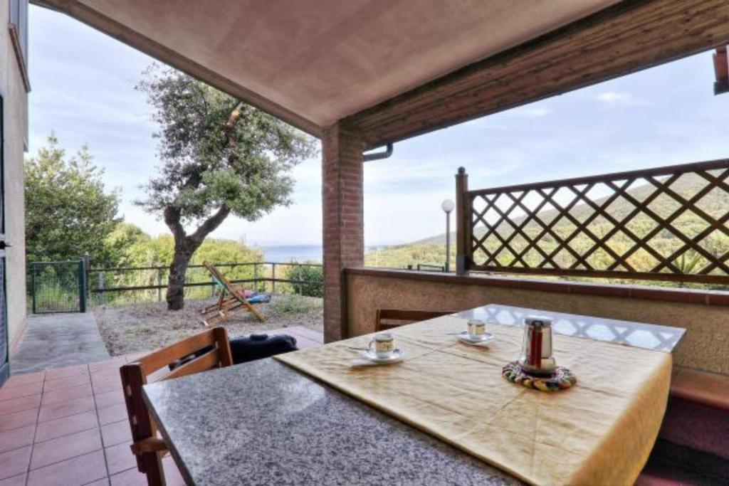 a table and chairs on a porch with a view of the ocean at Appartamenti Le Querce App. Ginestra in Capoliveri