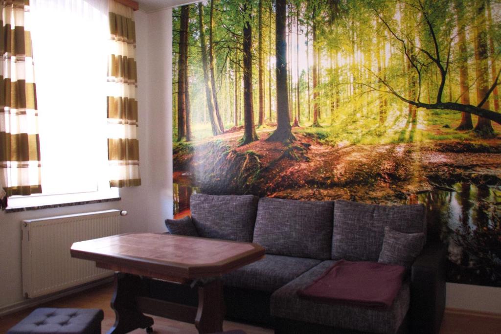 a living room with a couch and a forest mural at Ferienwohnung Rose in Schöneck