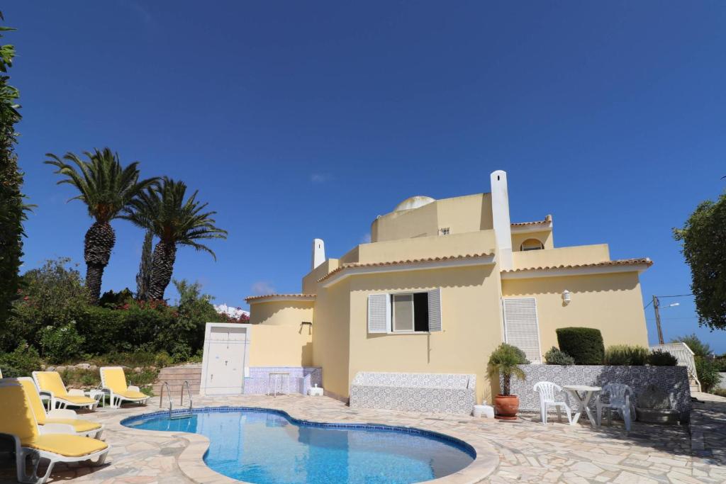 a villa with a swimming pool in front of a house at Villa Carvoeiro Ceu in Lagoa