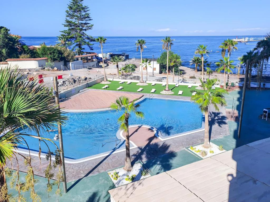an overhead view of a swimming pool with palm trees and the ocean at Costamar Oceanview 1 Bed Apartment in Arona