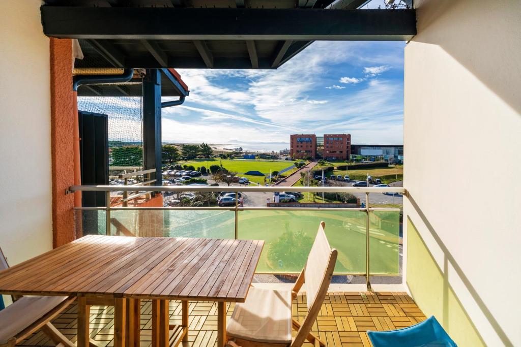 a balcony with a wooden table and chairs at Superbe Appartement Vue Océan in Capbreton