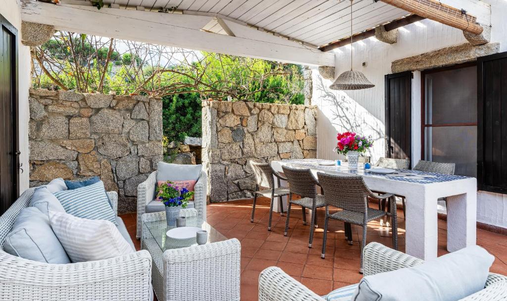 a patio with a table and chairs and a stone wall at Casa 2 in Castiadas