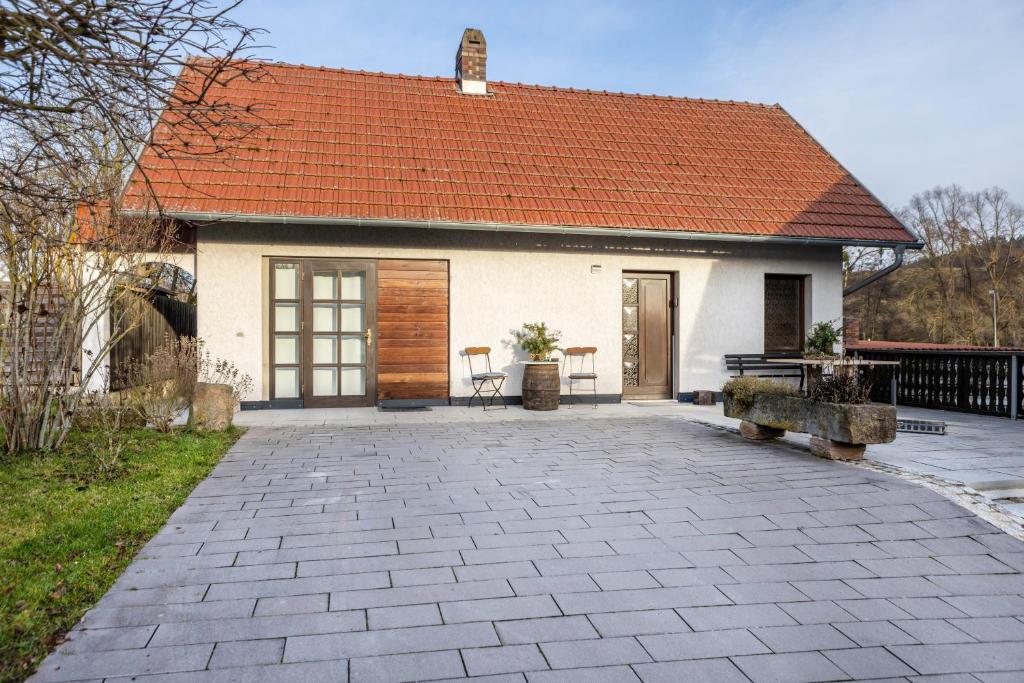 a white house with an orange roof and a patio at Ferienhaus Felsenblick in Rippershausen
