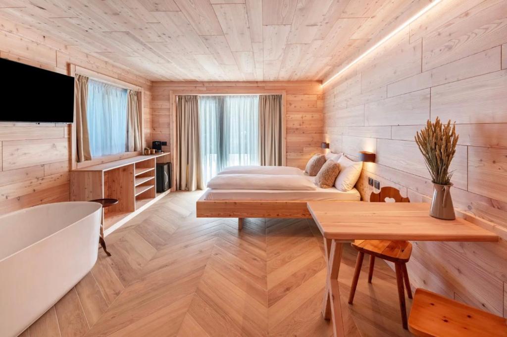 a bedroom in a log cabin with a bed and a tub at Noah Suites in Vigo di Fassa