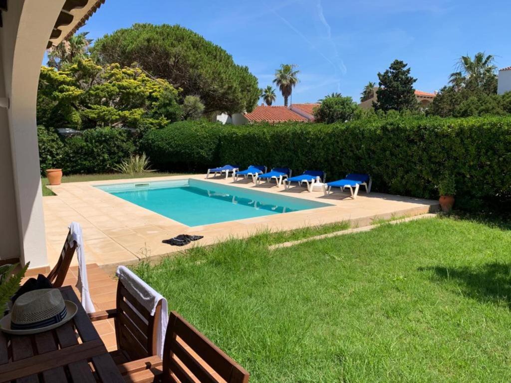 a swimming pool in a yard with chairs around it at Miret in Cala en Bosc