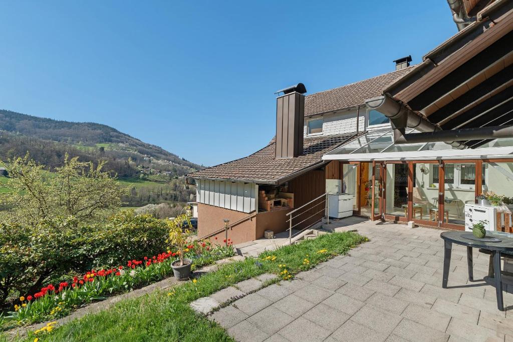 a house with a patio with a table and flowers at Ferienwohnung Gabriele in Lauf