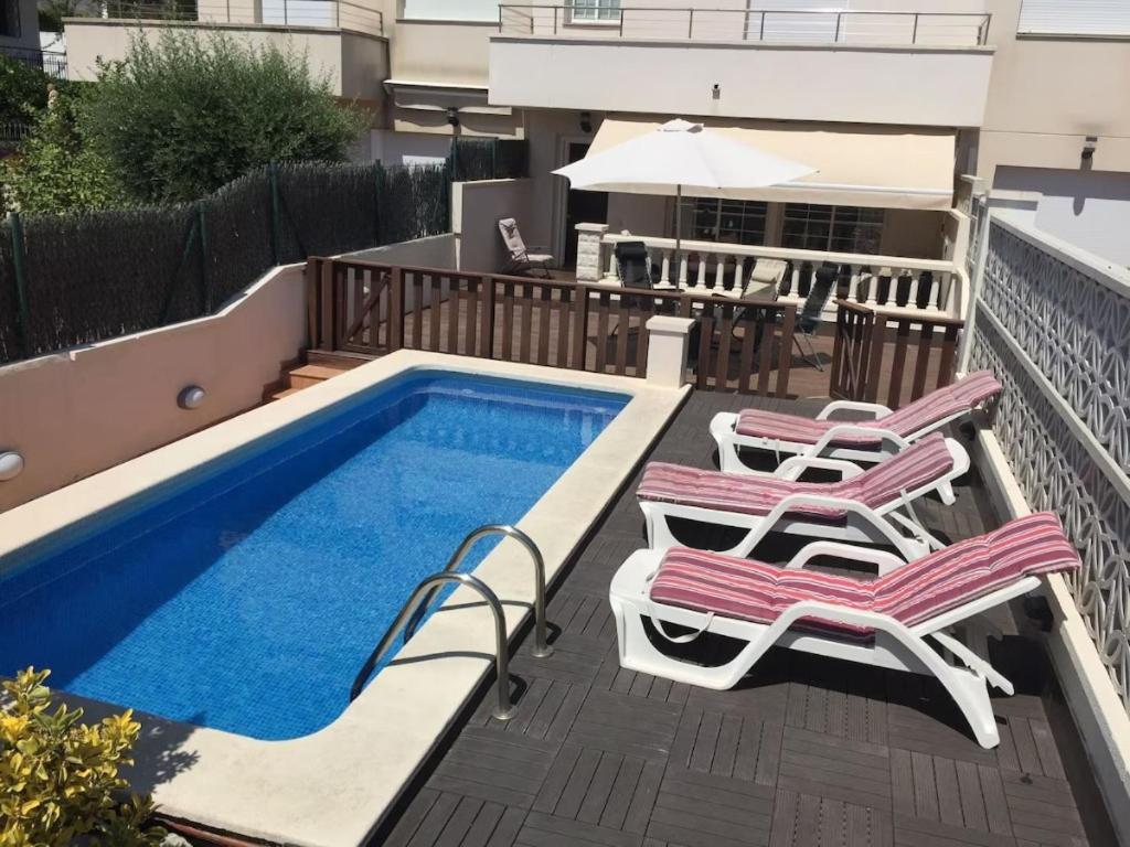 a deck with chairs and a swimming pool at Sitges Llum House in Sitges