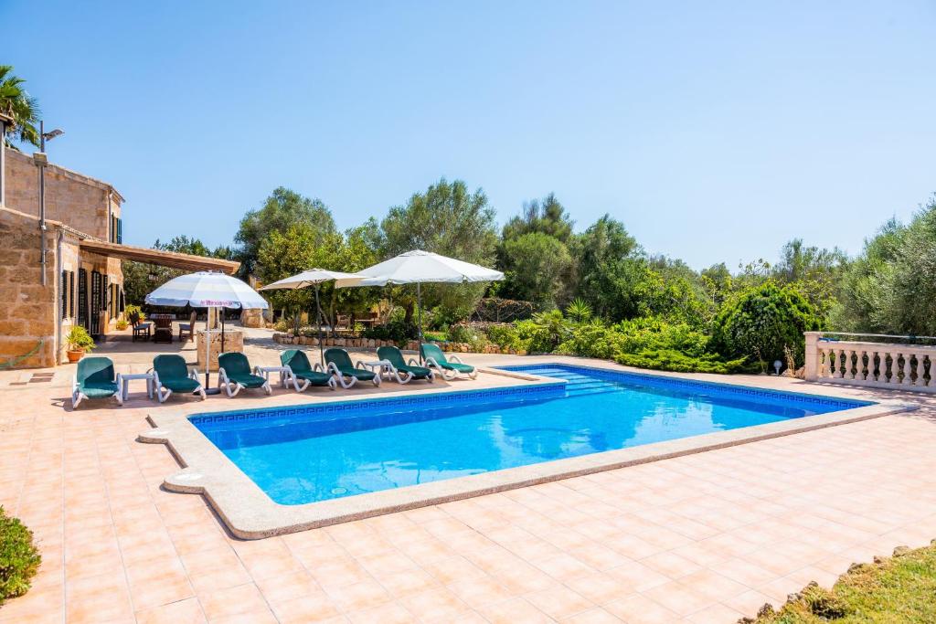 a swimming pool with chairs and umbrellas in a yard at Can Colau in Santa Margalida