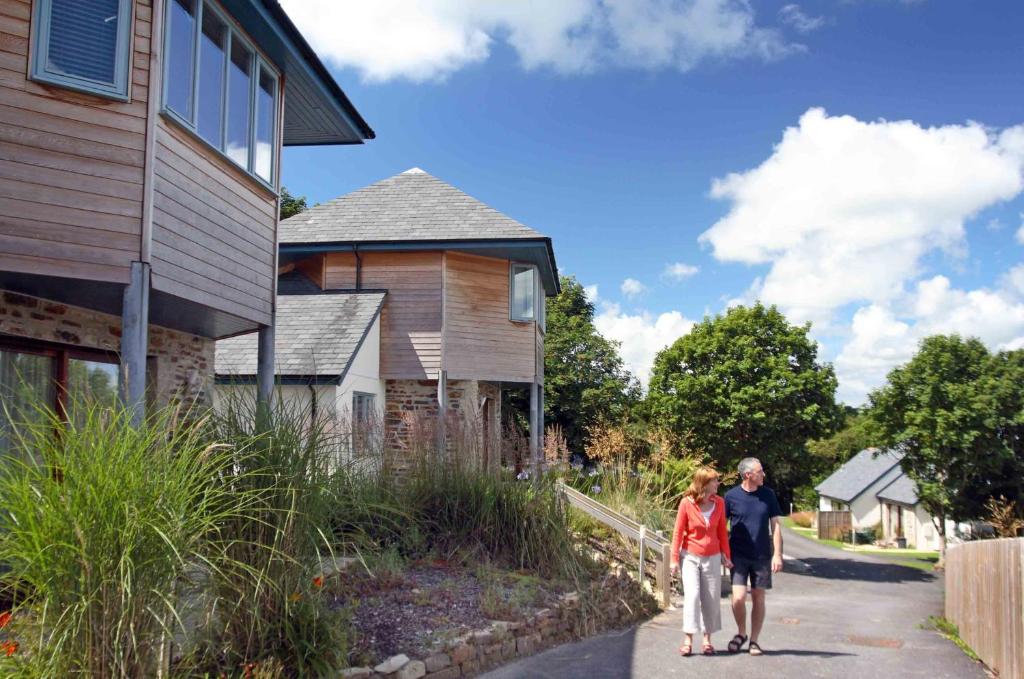 a man and a woman walking down a sidewalk next to a house at The Valley in Perranwell