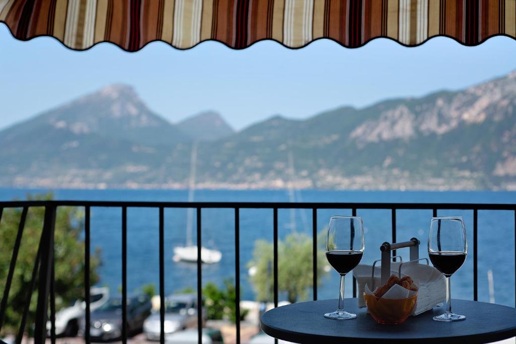 two glasses of wine sitting on a table on a balcony at Appartamento Marilu Lake View in Brenzone sul Garda