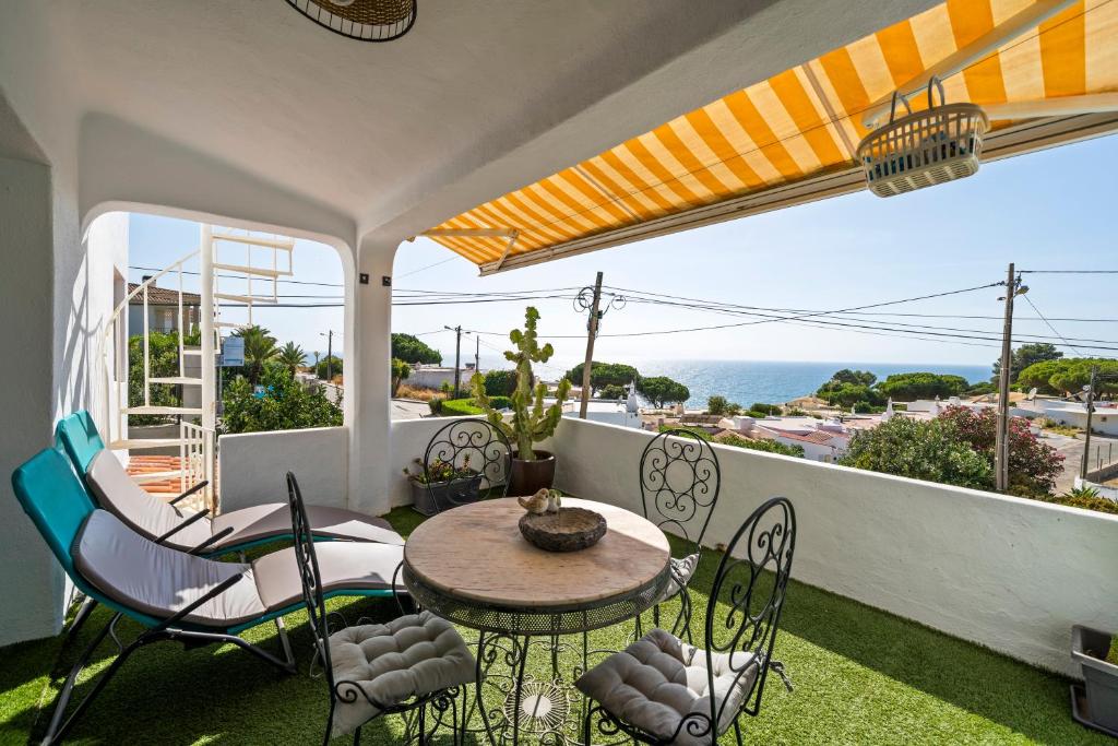 a patio with a table and chairs and the ocean at Casa Gudrun in Praia do Carvoeiro
