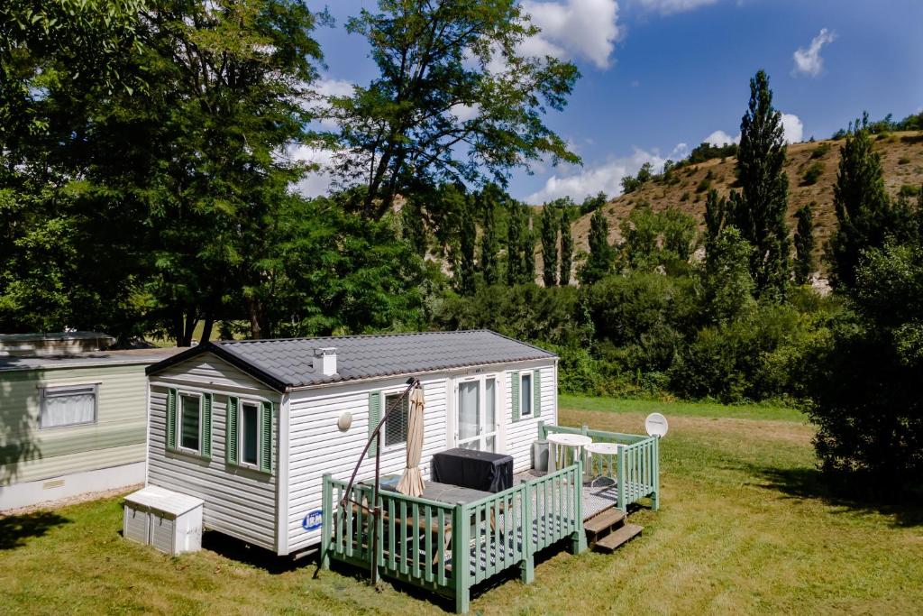 a white tiny house with a porch in a field at Mobilhome Le Cocon in Saint-Pompont