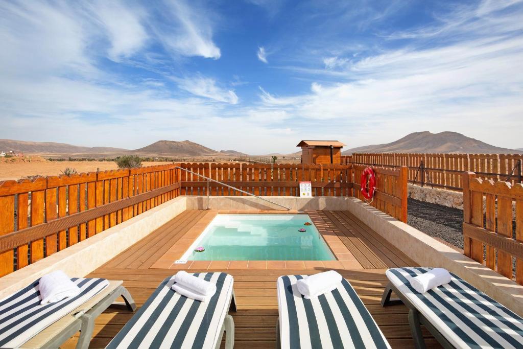 a swimming pool on a wooden deck with two chairs at Casa Glory in Antigua