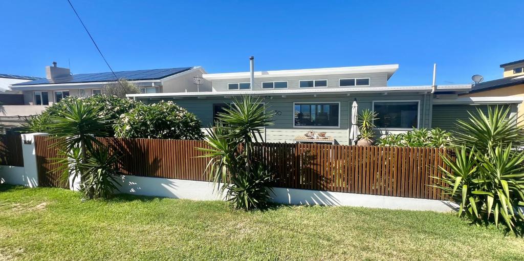 a fence in front of a house with palm trees at The G Shack at Rennies Beach in Ulladulla