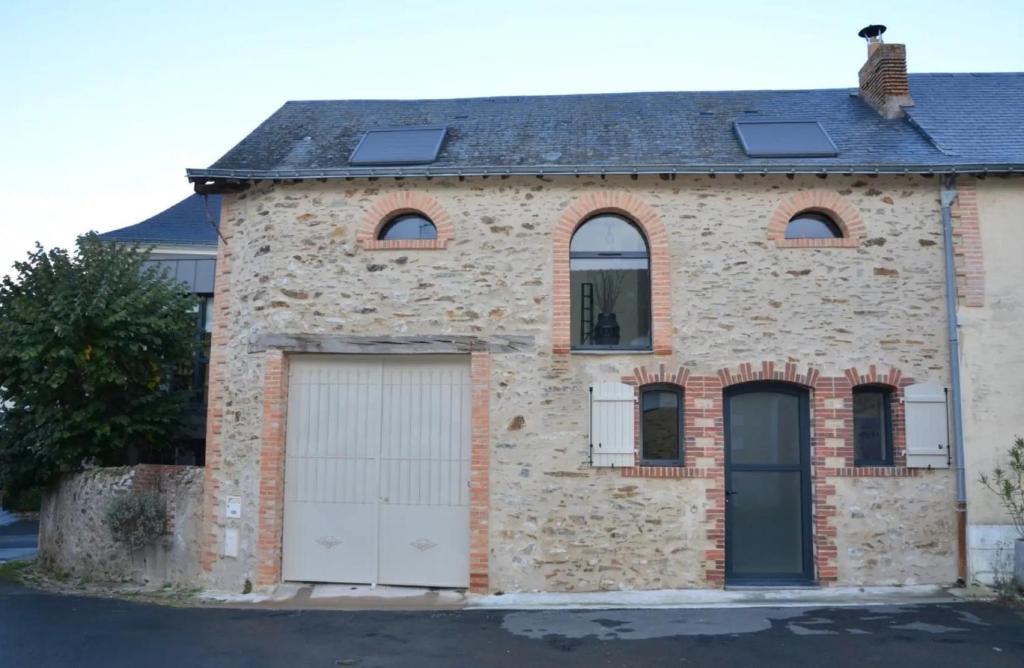 a brick house with two garage doors and two windows at Chambres D'hôtes Le Fer À Cheval in Montreuil-sur-Maine