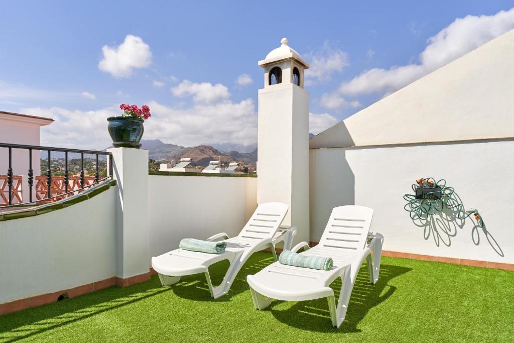 a balcony with two chairs and a table on the grass at Casa Murillo in Nerja