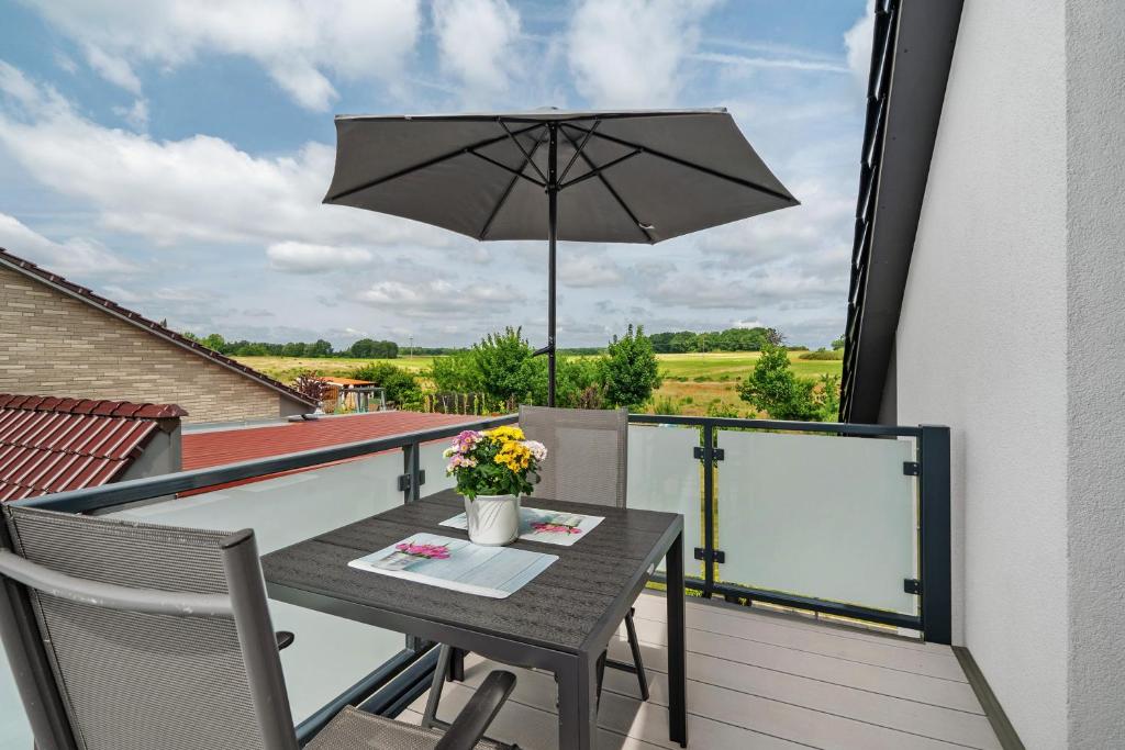 a table and chairs on a balcony with an umbrella at Ferienwohnung Auszeit in Kargow