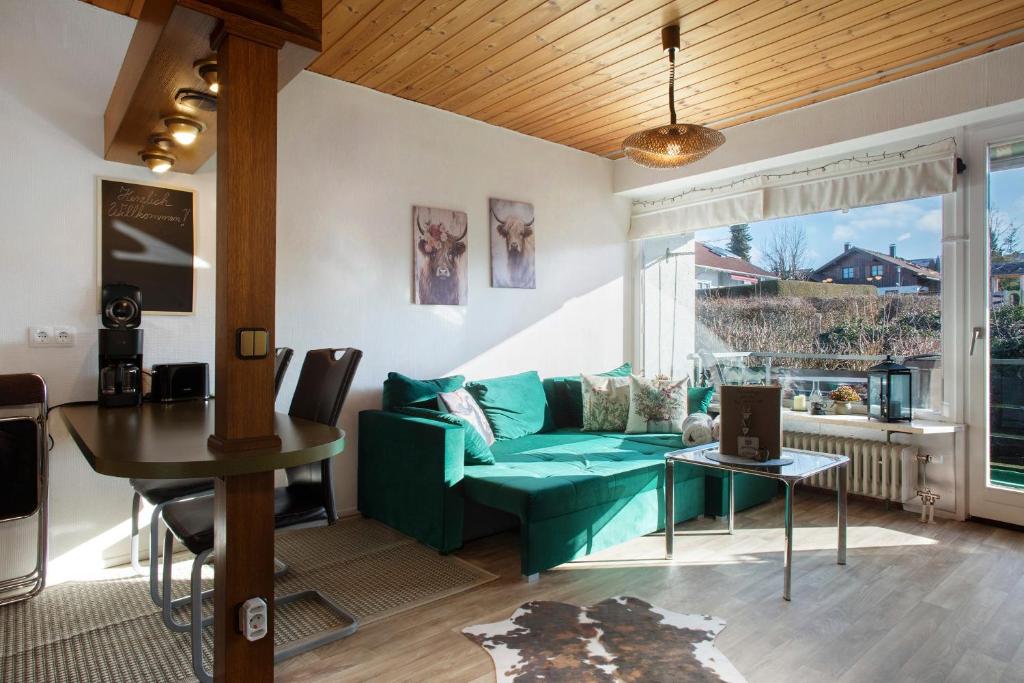 a living room with a green couch and a table at Appartment Gute Zeit in Weiler-Simmerberg