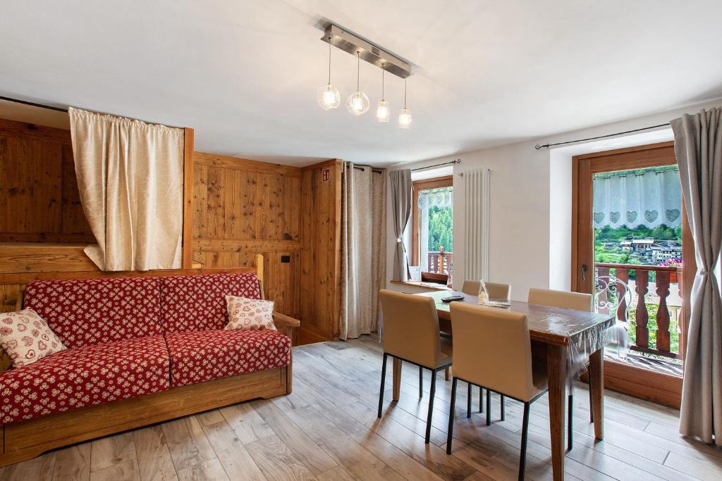 a living room with a red couch and a table at Les Cles - Achillea in Valsavarenche