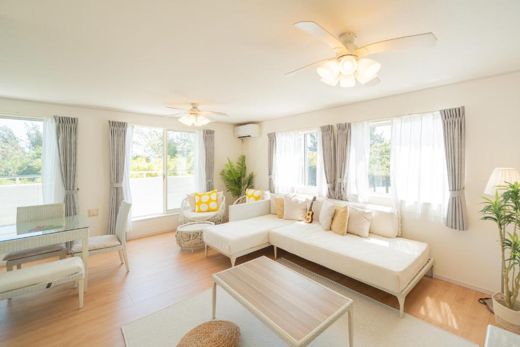 a living room with a white couch and a table at 照間Terumaの美しい海Mareまで徒歩30秒リビング広々快適 TERUMAREテルマーレ in Uruma