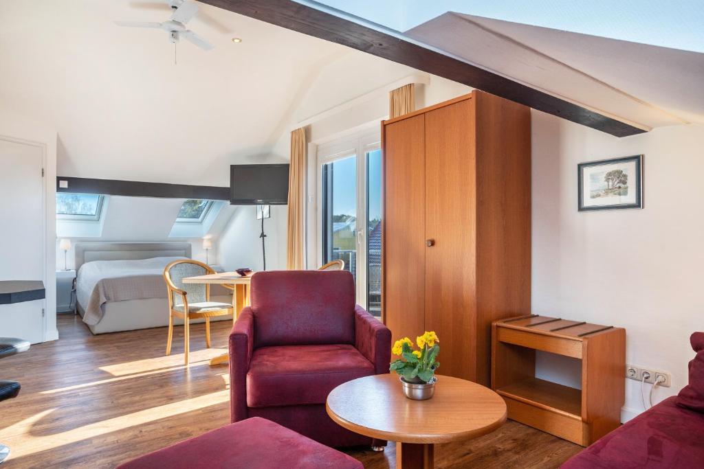 a living room with a red chair and a bedroom at Haus Ostseesonne in Baabe