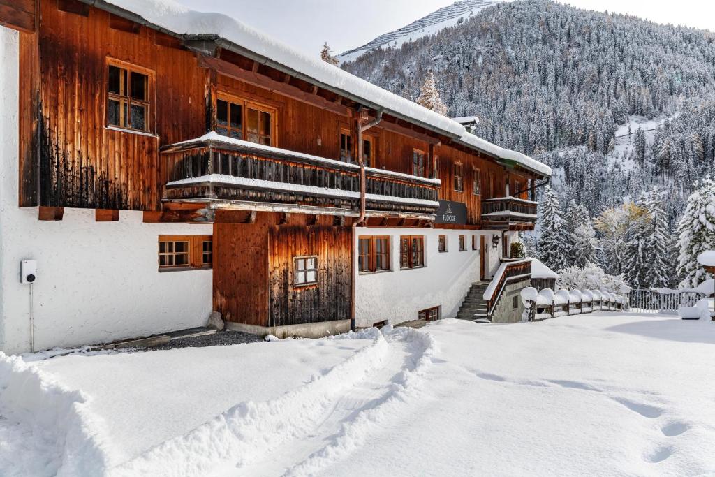 a building covered in snow with a mountain in the background at Chalet Flocke Appart Murmeltier in Sankt Anton am Arlberg