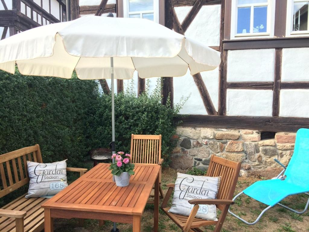 a wooden table and chairs with an umbrella at Logierhaus An der Truse in Brotterode