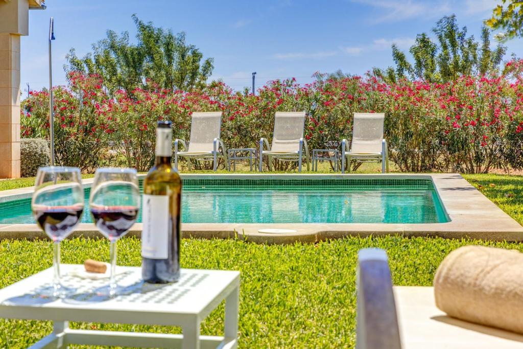 a bottle of wine and two glasses on a table next to a pool at Finca Sa Pradera in Palma De Mallorca