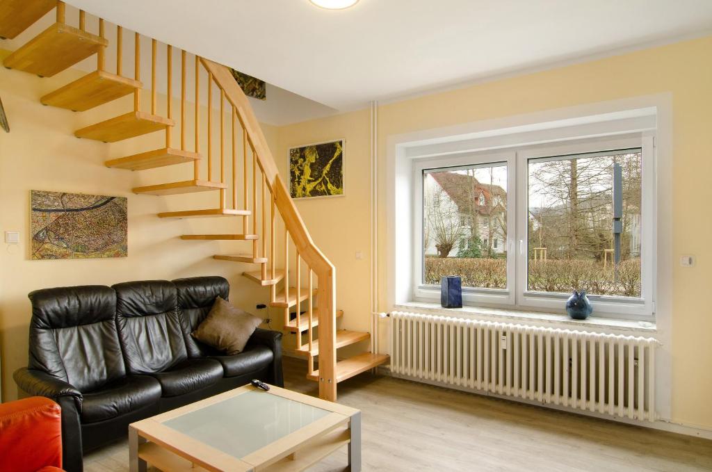 a living room with a staircase and a leather couch at Haus unterm Räuschenberg in Höxter