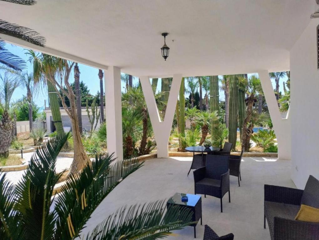 a patio with a table and chairs and palm trees at Villa Bludea - Salento in Torre Lapillo