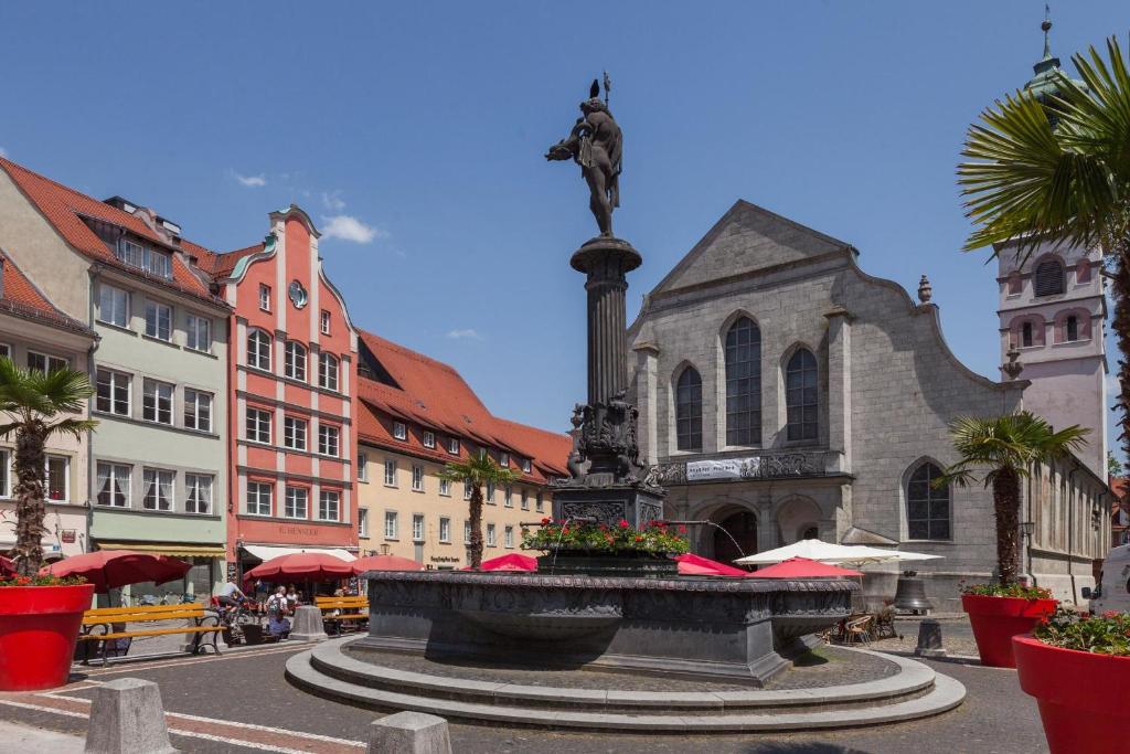 a fountain in the middle of a city with a church at Ferienwohnungen Hensler in Lindau