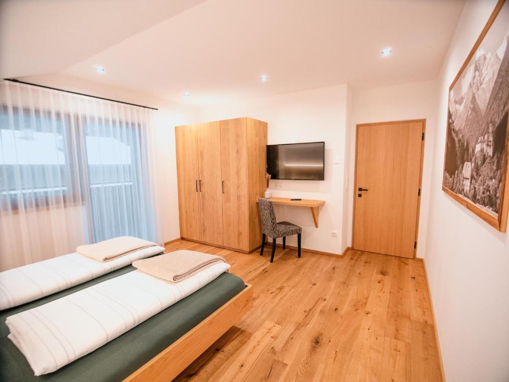 a room with two beds and a desk and a television at Zum Sonnentor App Pinus in Lutago