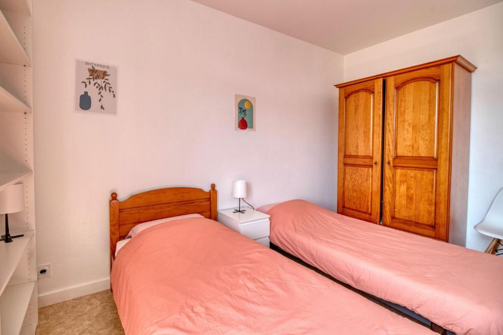 a bedroom with two beds and a wooden cabinet at Chambre double à Toulouse in Toulouse
