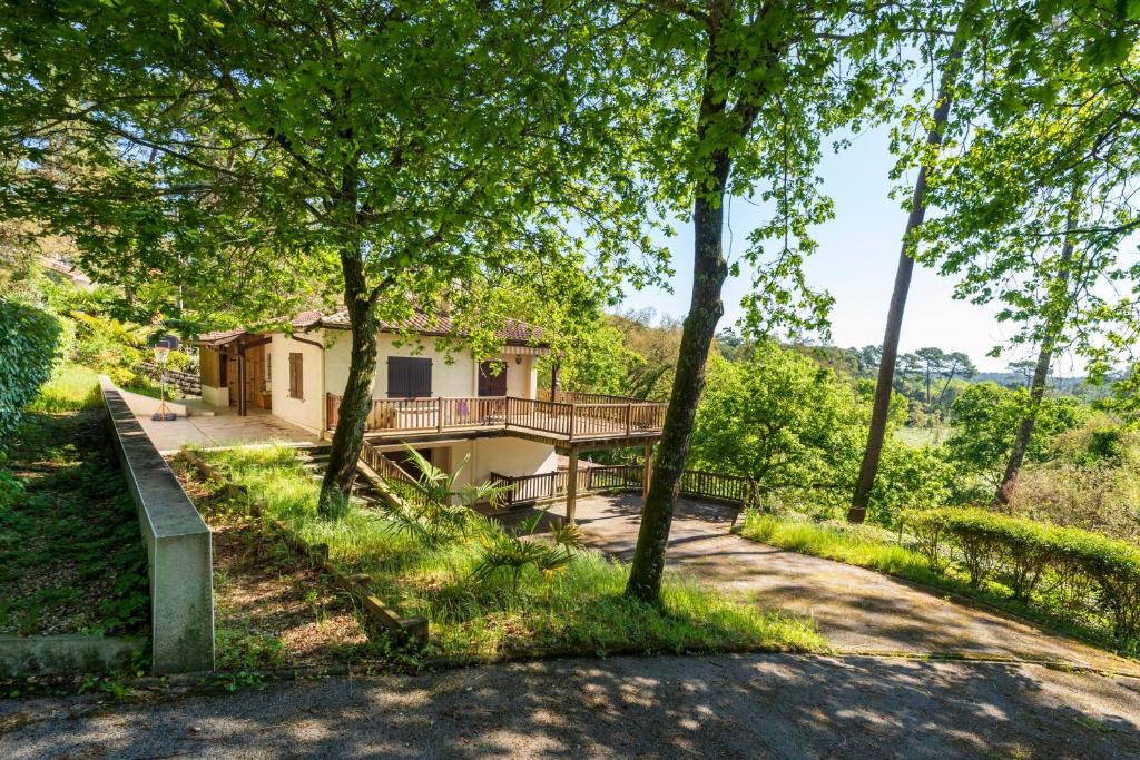 a house in the woods with a walkway and trees at Studio Proche Lac Hossegor in Hossegor