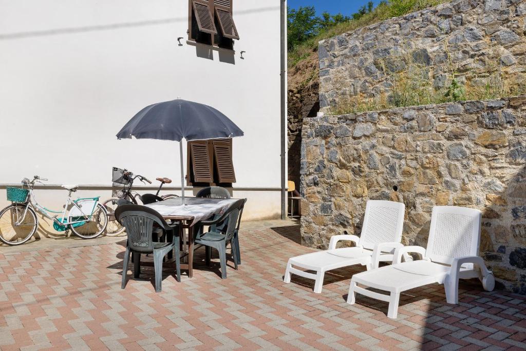 a patio with a table and chairs and an umbrella at La Casa Sul Lago in Osiglia