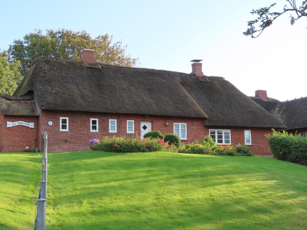a large red brick house with a thatched roof at Große Warf mit Rasenfläche in Ockholm
