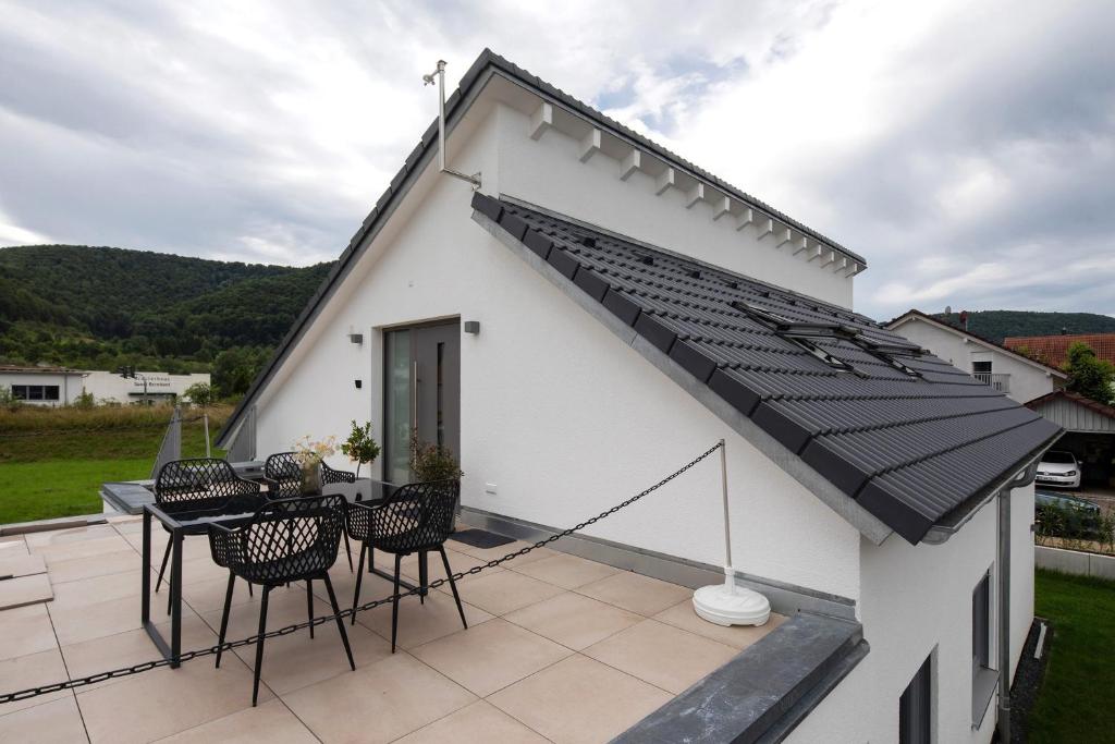 a house with a black roof and a patio at Ferienwohnung 6 in Bad Ditzenbach
