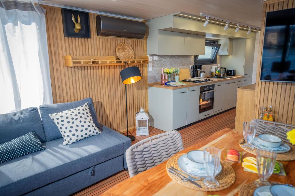 a living room with a blue couch and a kitchen at Exklusives Naturerlebnis Roxy in Fürstenberg