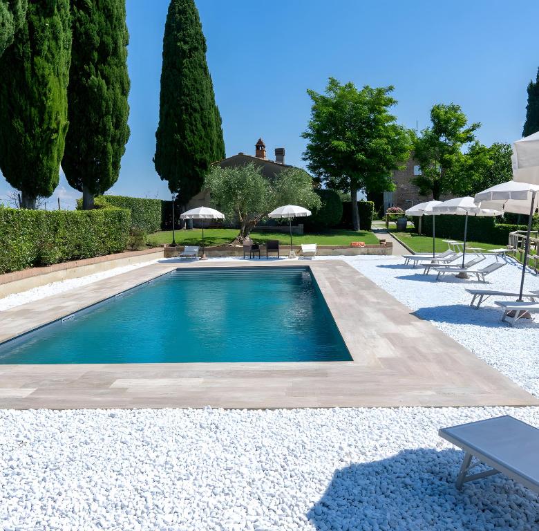 a swimming pool with trees and umbrellas at Villa Arnilù in San Gimignano