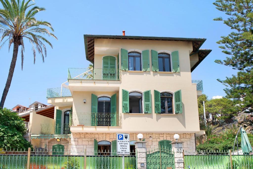 a house with green shutters and a palm tree at Capriccio in Bordighera