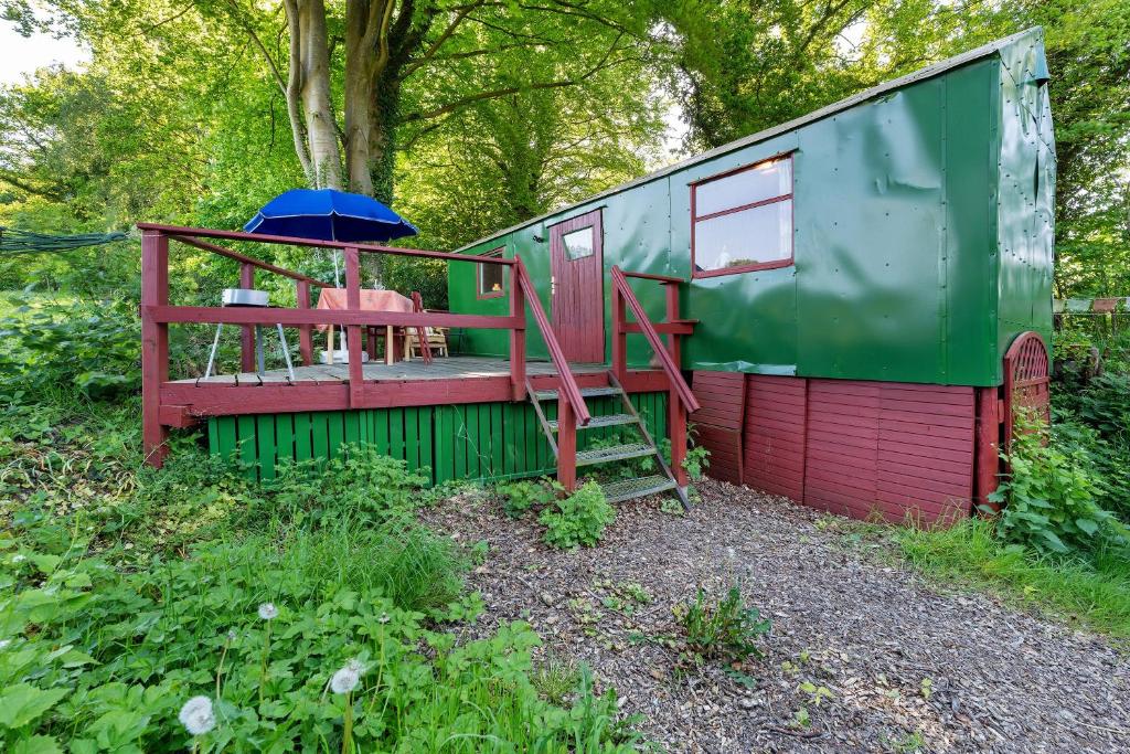a green and red house with a table and an umbrella at Ferien Tinyhaus im Tale in Ascheffel