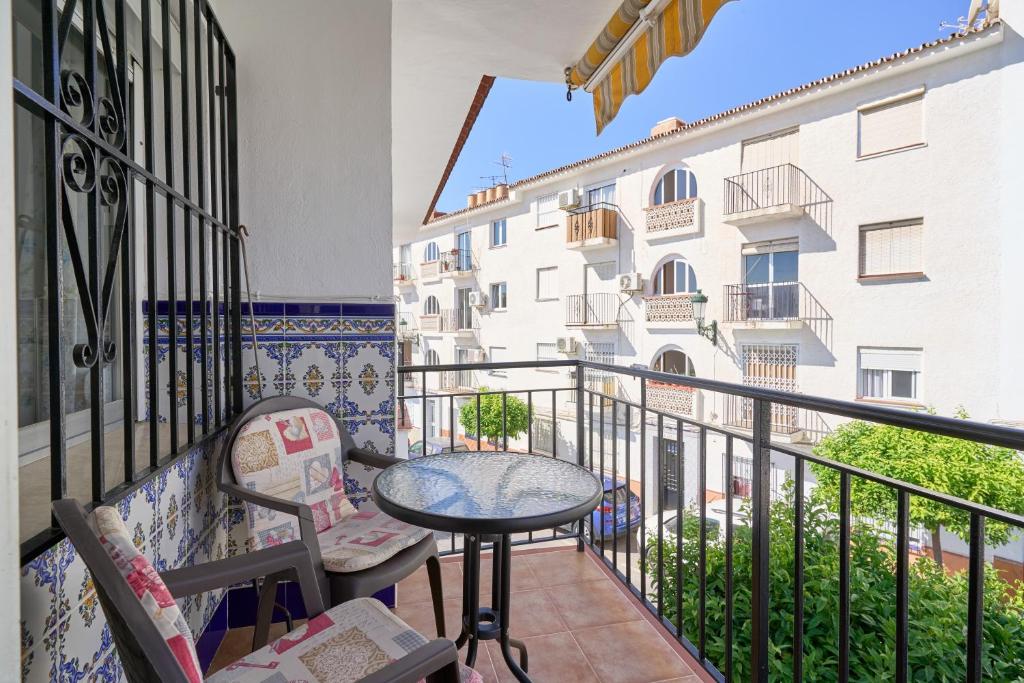 a balcony with a table and chairs and a building at Apartmento Los Alamos in Nerja