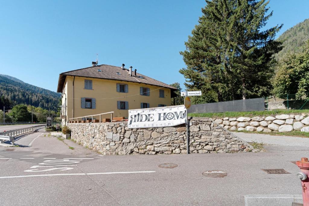 a sign in front of a stone wall next to a house at Appartamenti Ride Home in Commezzadura